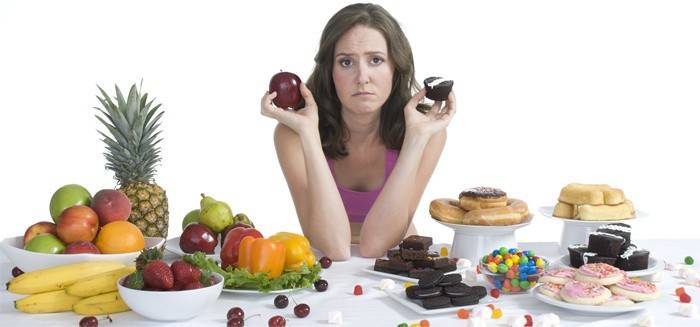 La fille choisit entre des bonbons et des fruits.