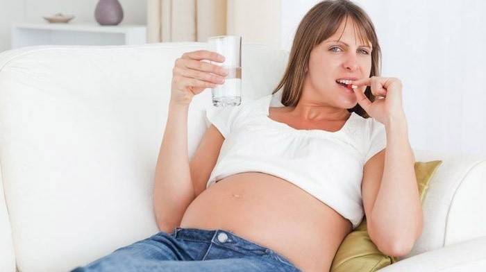 Mulher grávida bebe vitaminas com cálcio