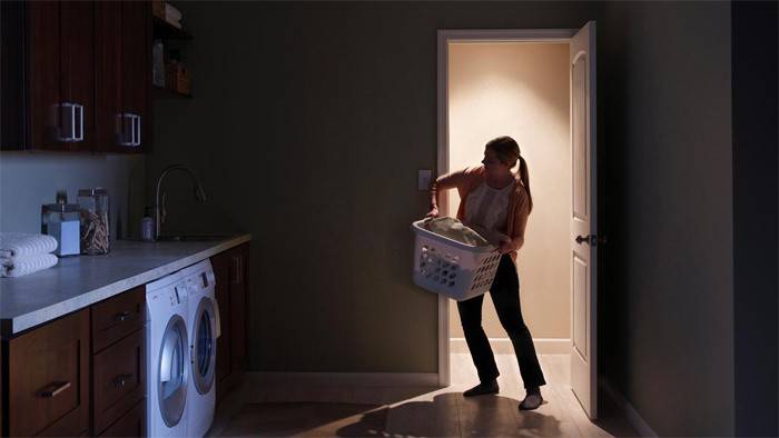 Chica buscando un interruptor en la habitación