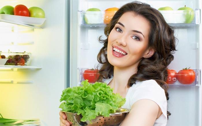 La ragazza mette l'insalata in frigo