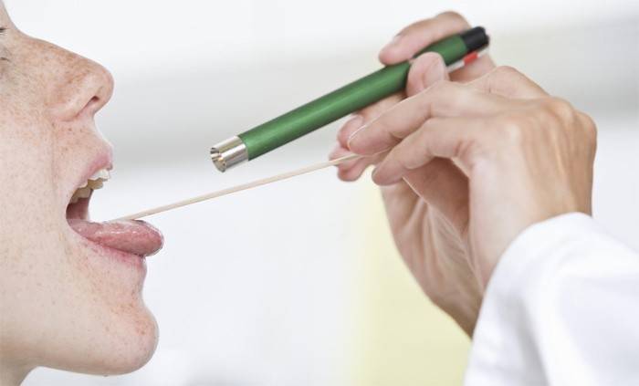 Il medico esamina la gola di un paziente