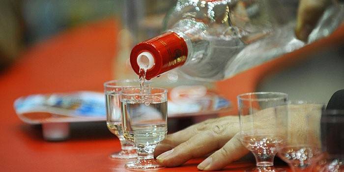 Man gießt ein Getränk aus einer Flasche
