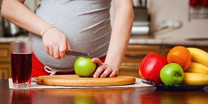 Mädchen im achten Monat schwanger schneidet Früchte
