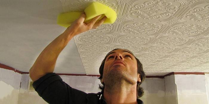 Mann klebt Tapete an die Decke