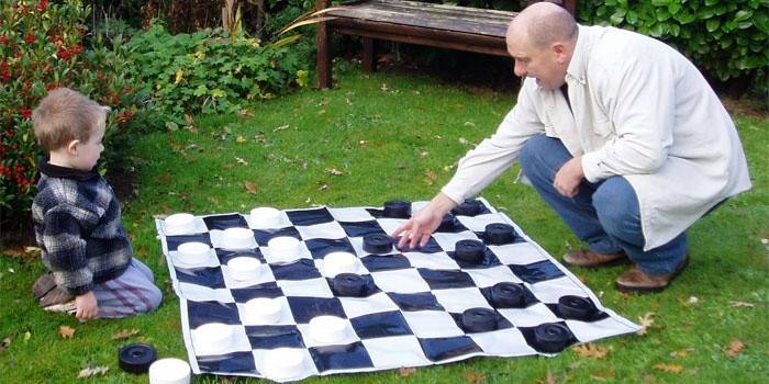 Pai ensina a criança a jogar damas