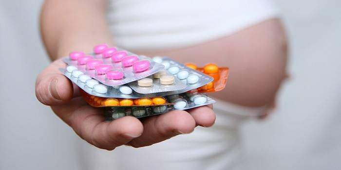 Una dona embarassada té pastilles hormonals a la mà