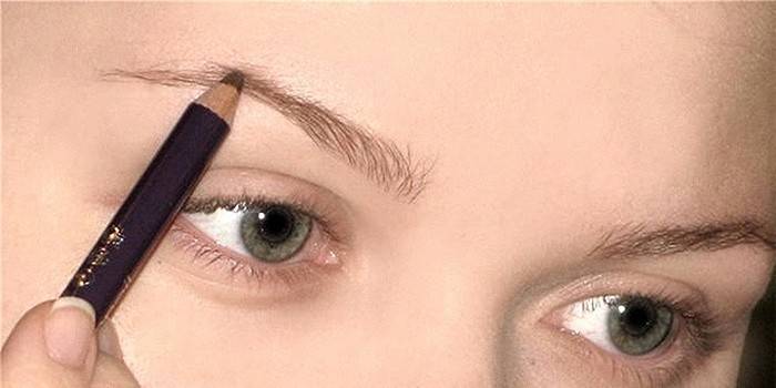Fille se maquille avec un crayon