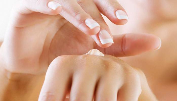 Fille frotte les mains avec de la crème