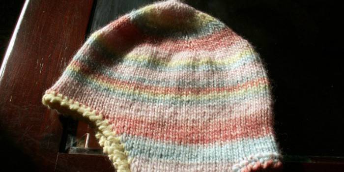 Un gorro con orejeras para un niño tejido con sus propias manos sobre agujas de tejer