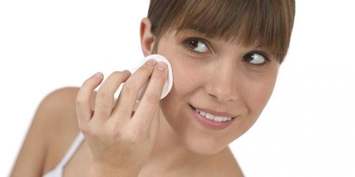 Fille essuie son visage avec un coton