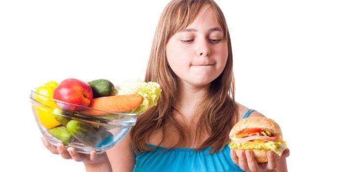 Ragazza con frutta e un hamburger