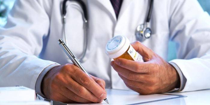 Un médecin rédige une ordonnance et tient un paquet de pilules