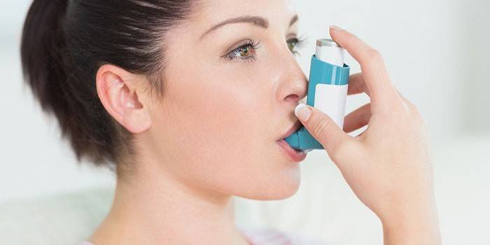Chica con inhalador para el asma en la boca