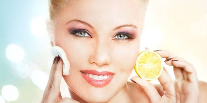 La donna si strofina il viso con il succo di limone
