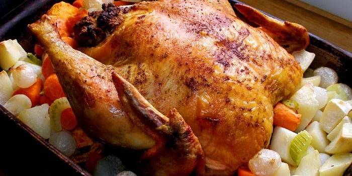 Frango inteiro com legumes em uma assadeira