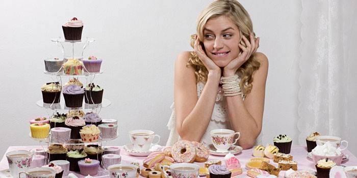 Ragazza che si siede al tavolo con i dolci