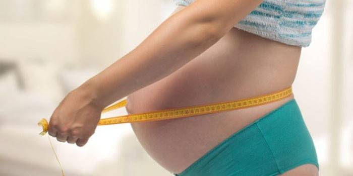 Schwangere Frau mit Zentimeter