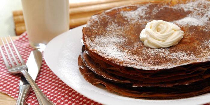 Ein Stapel Schokoladenpfannkuchen auf einer Platte mit Sahne