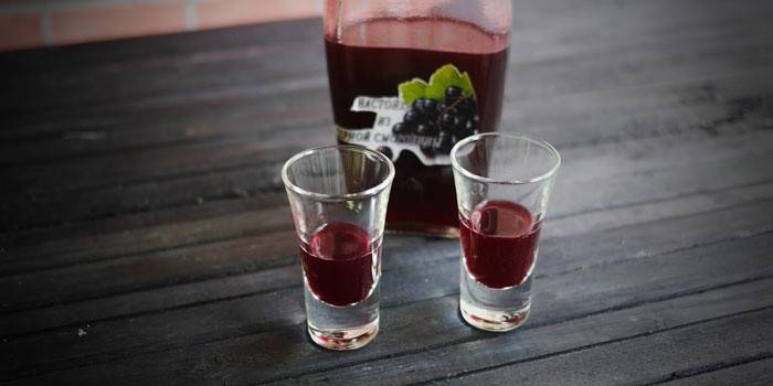 Tintura di ribes in una bottiglia e bicchieri