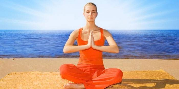 La ragazza medita nella posizione del loto sulla costa.