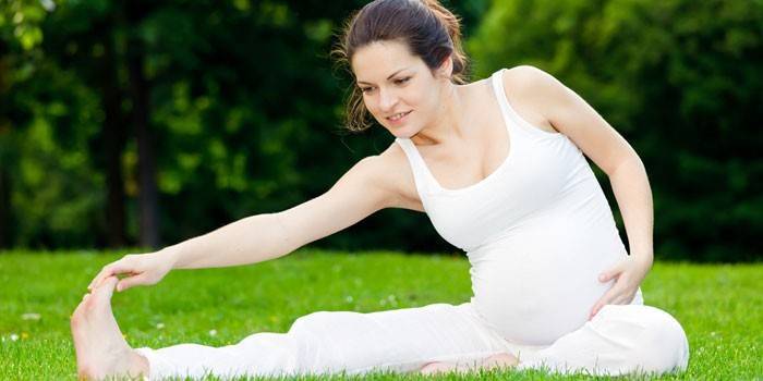 Menina grávida se exercita na natureza.