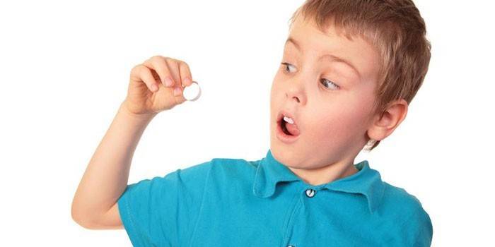 Il bambino tiene una pillola in mano