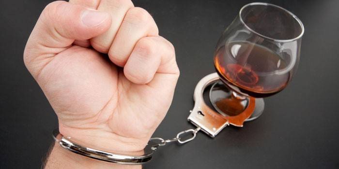Χέρι, χειροπέδες και κονιάκ σε ένα ποτήρι