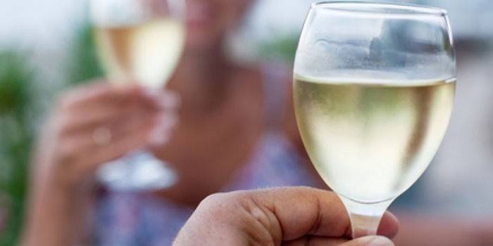 Un pahar de vin alb în mâna unei femei