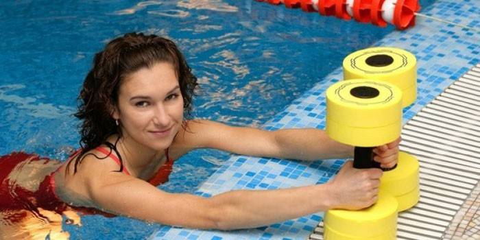 Ragazza in piscina con manubri