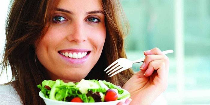 Jente holder en tallerken med salat