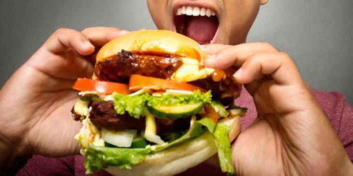 Adamın elinde bir hamburger ile