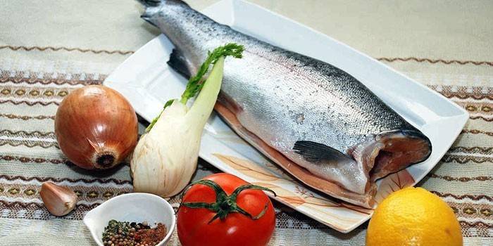 Trucha sin cabeza en un plato, verduras, limón y especias.