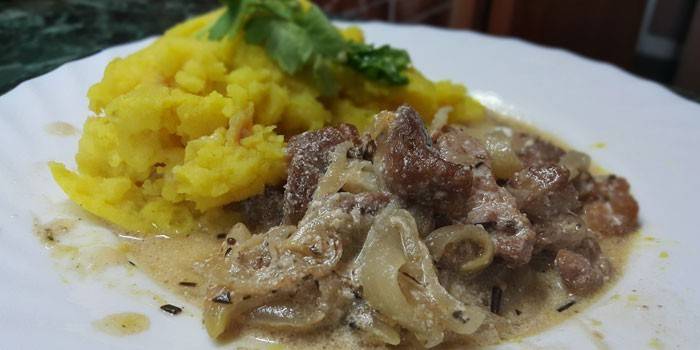 Carne de porco fatiada cozida com cebola em molho de creme de leite e purê de batatas