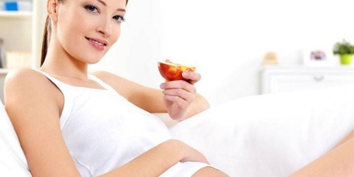 Niña embarazada con una manzana en la mano
