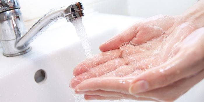 Mädchen wäscht die Hände unter dem Wasserhahn