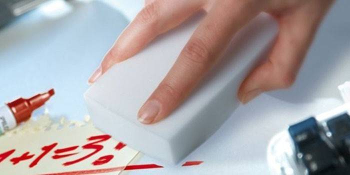 La spugna di melamina cancella l'iscrizione con un pennarello