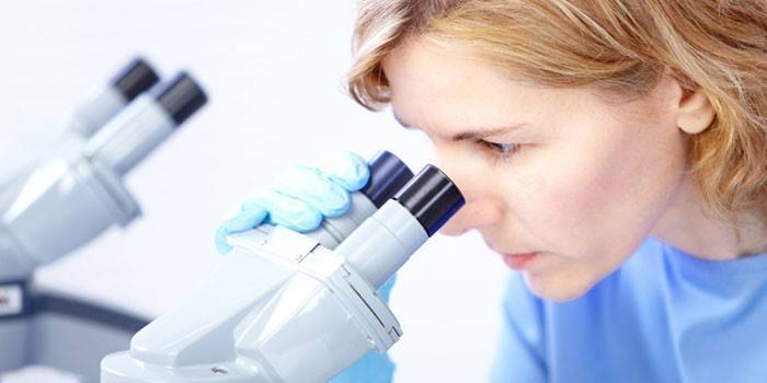 Ragazza che osserva tramite un microscopio