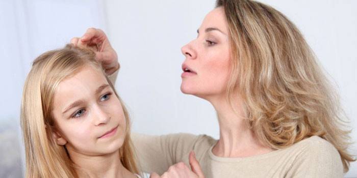 Una mujer examina la cabeza de una niña