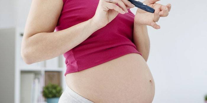 Schwangeres Mädchen überprüft Blutzucker mit einem Glukometer