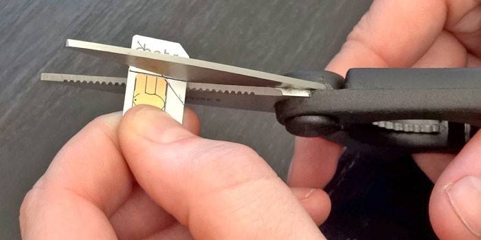 Un homme coupe une carte SIM selon le modèle avec des ciseaux