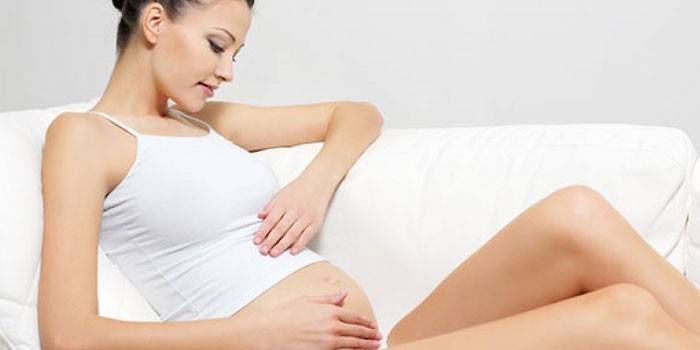 Ragazza incinta che si siede su un divano