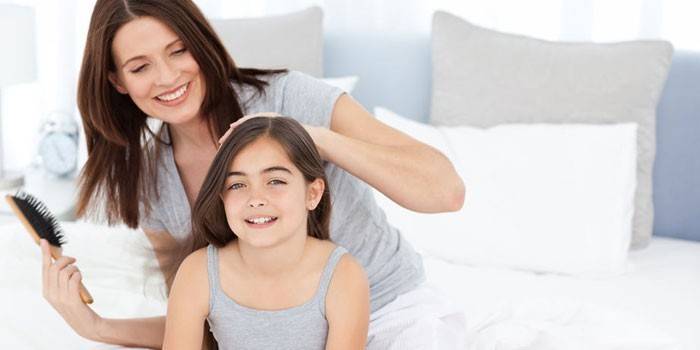 Mujer peinando el cabello de una niña