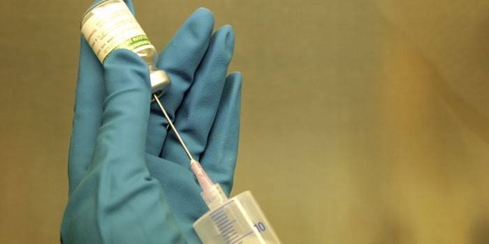 Siringa e bottiglia con il farmaco in mano