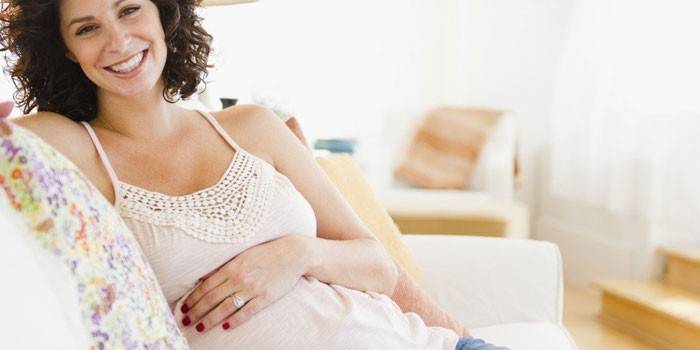Ragazza incinta che si siede su un divano