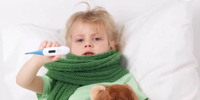 A gyermek ágyban fekszik, és elektronikus hőmérőt tart a kezében