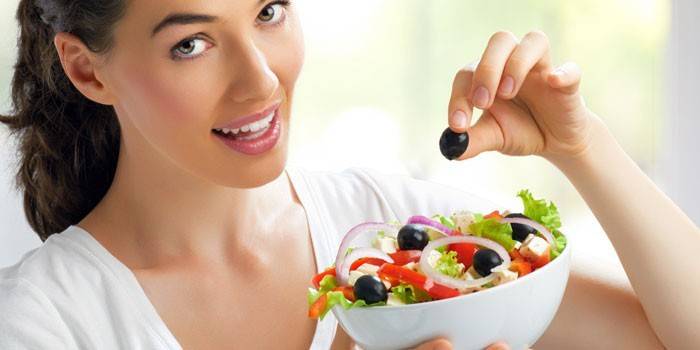 La ragazza tiene un piatto con insalata nelle sue mani