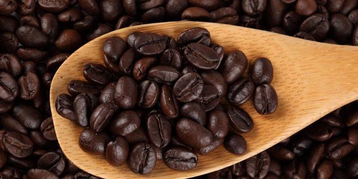 Forti chicchi di caffè tostati su una spatola di legno