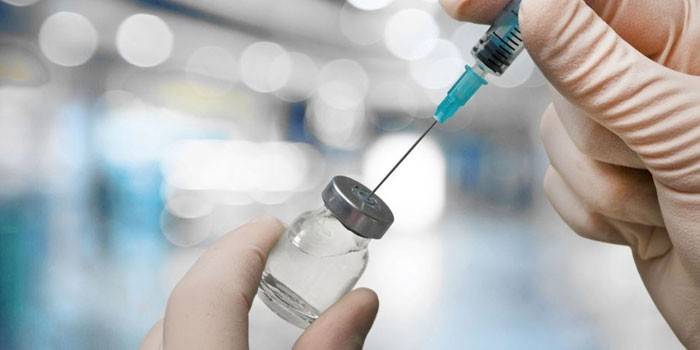 Σύριγγα και φιάλη με το φάρμακο στα χέρια ενός ιατρού