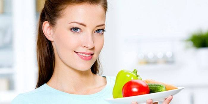 La ragazza tiene in mano un piatto con verdure