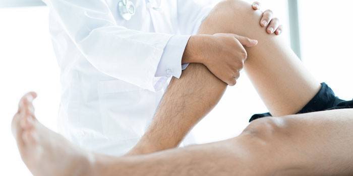 Medicul examinează picioarele pacientului